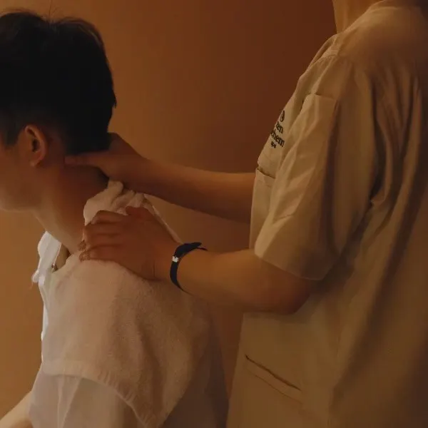 Therapist massaging a seated guest's neck and shoulders