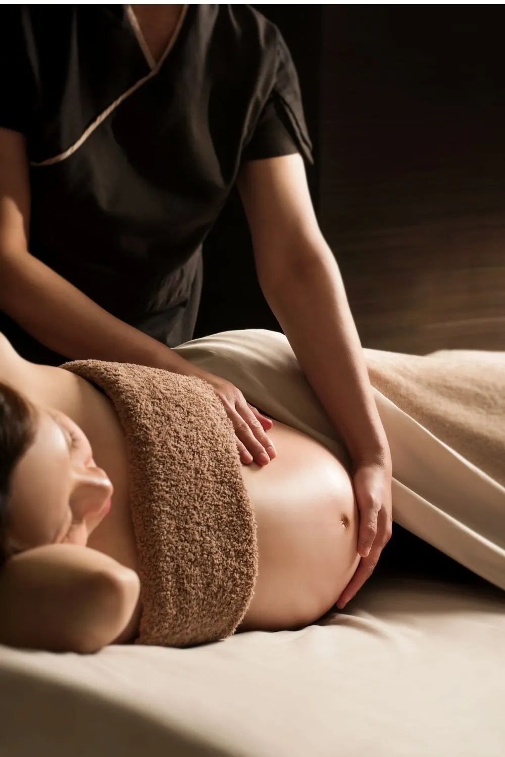 Therapist massaging a pregnant client under a towel