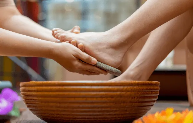Foot spa treatment over a wooden bowl